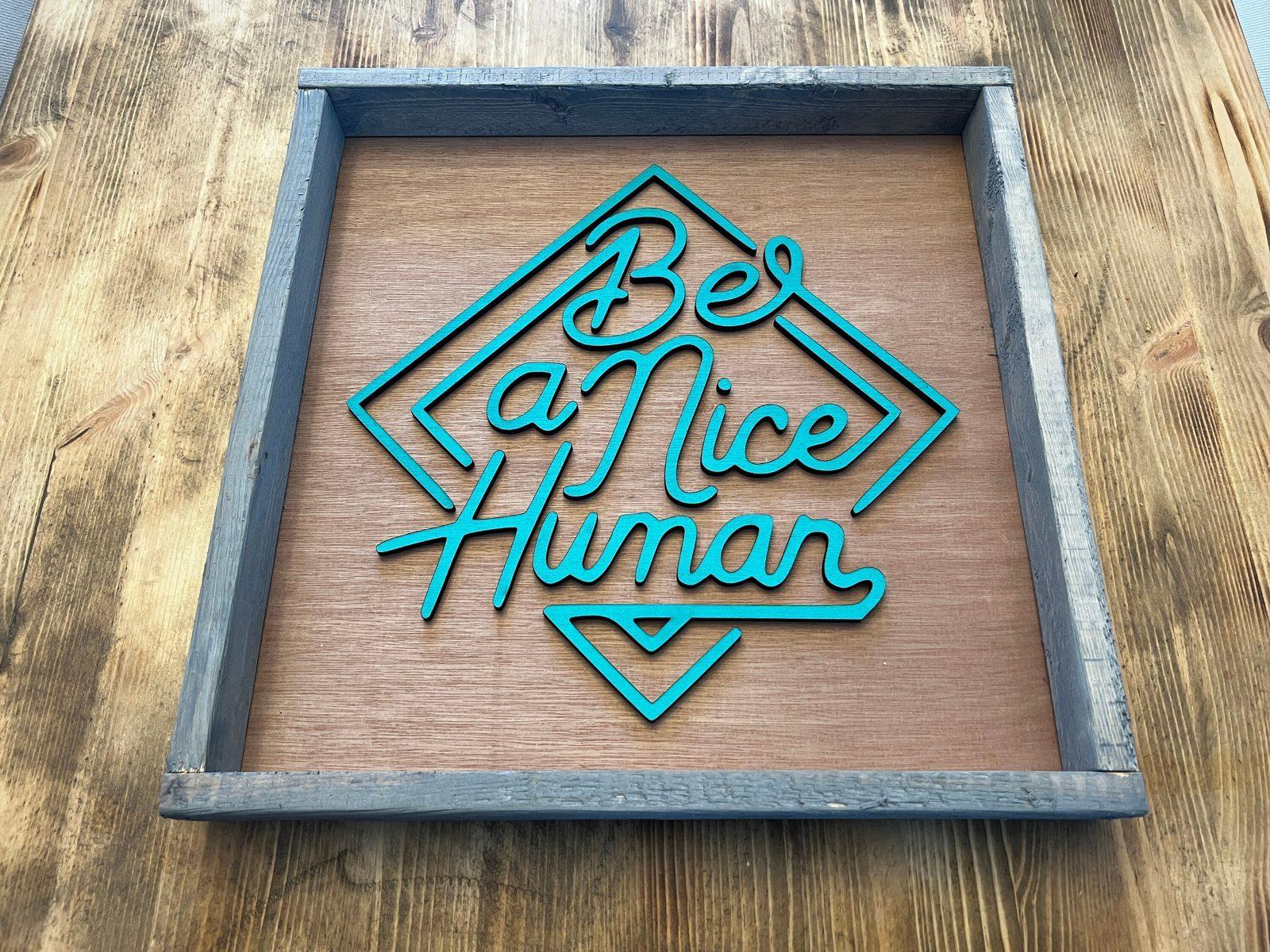 Be A Nice Human sign displayed on a wall
