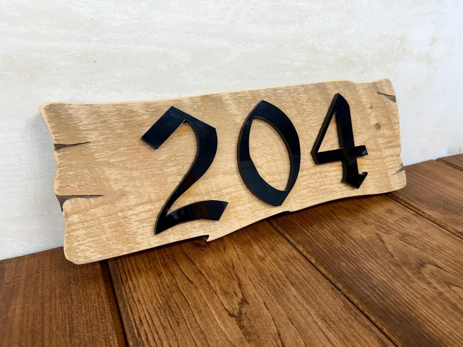 Live-edge wood address sign with raised black acrylic numbers made by The Boss Factory