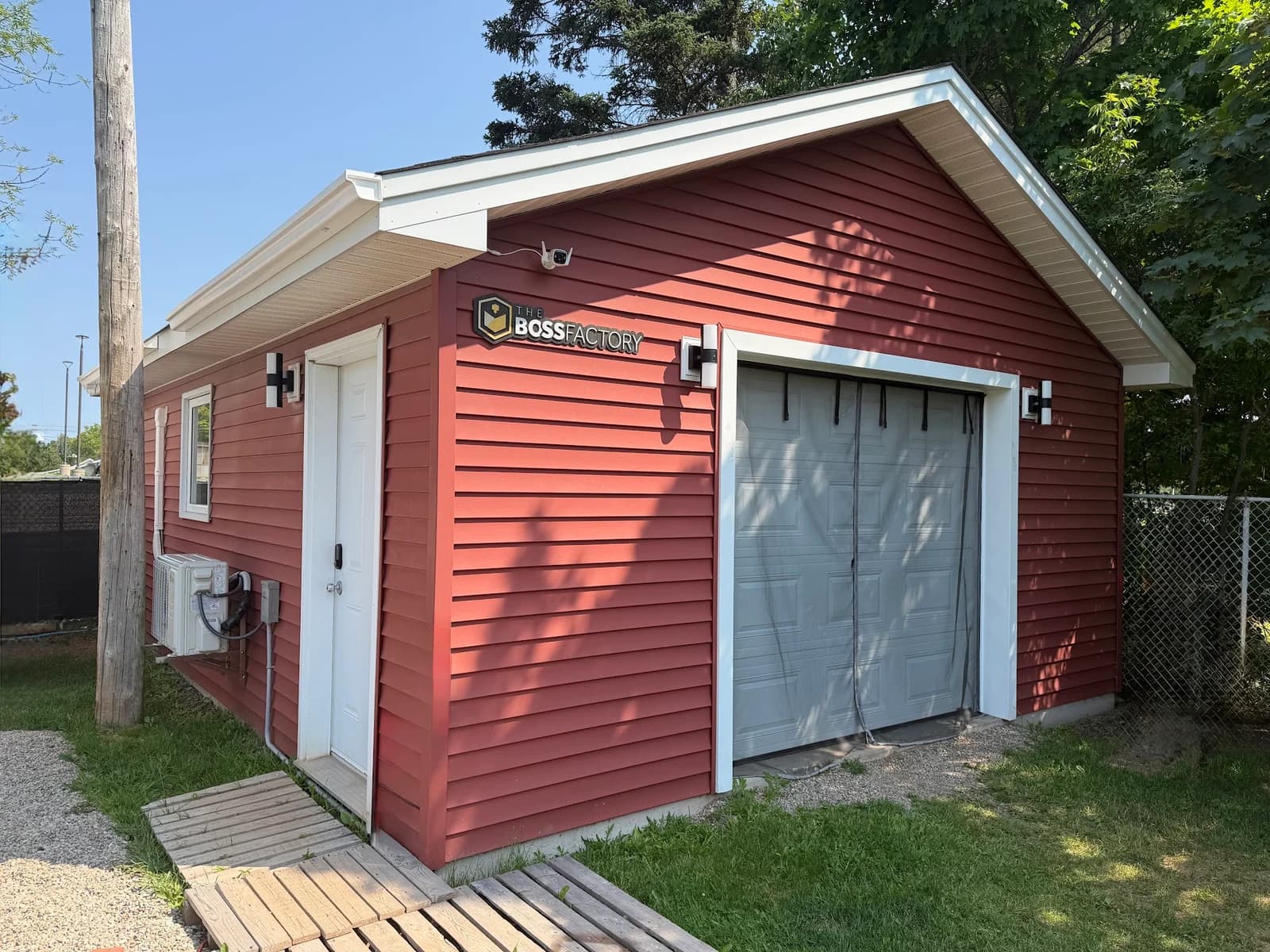 The red backyard workshop with The Boss Factory sign beside the door